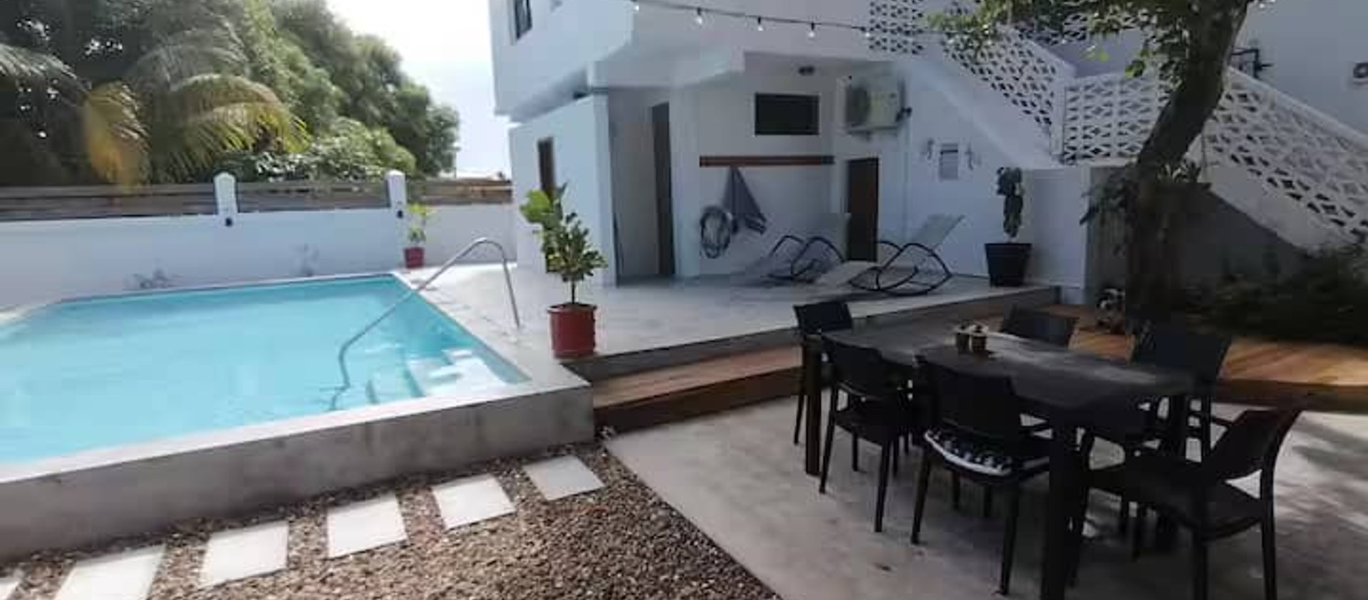 White two-story house with pool and patio seating at 14 cedar Dangriga