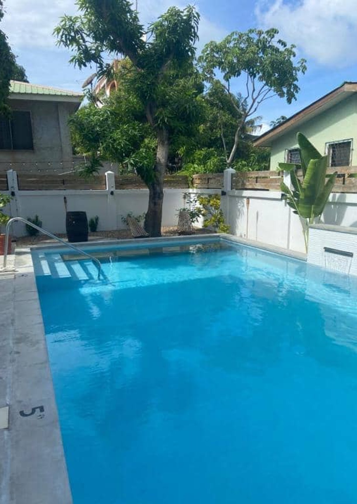 Blue swimming pool with stairs in residential backyard